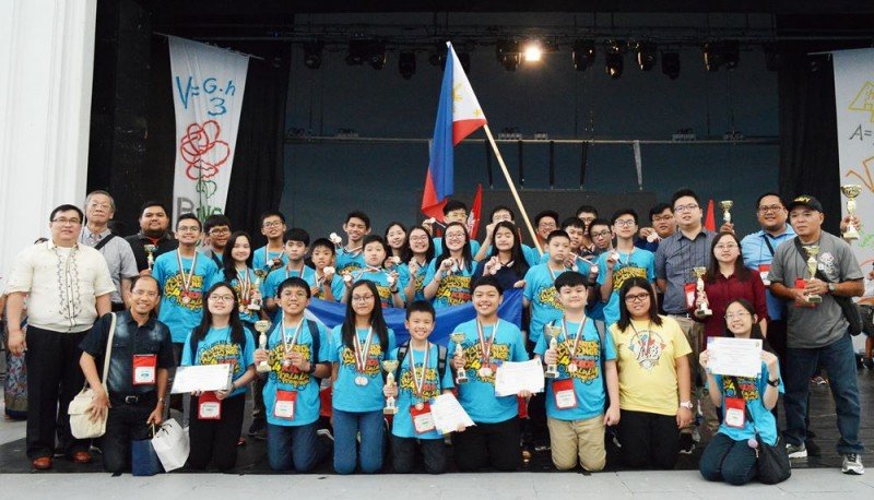 Filipino students together with their coaches wave the Philippine flag and show the medals and trophies they won at the awarding ceremony of the 2018 Bulgaria International Mathematics Competition (BIMC) in Burgas, Bulgaria. (Photo by MTG via PIA.gov.ph)