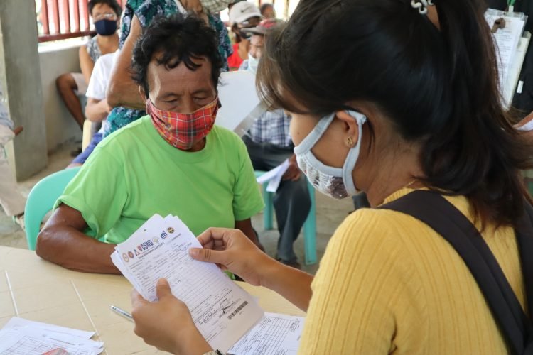 An LGU staff from Santa Maria, Romblon checks the Social Amelioration Card (SAC) form of one of the 1,555 qualified beneficiaries in the municipality during the distribution of the P5,000 emergency subsidy under SAP. (DSWD Mimaropa)