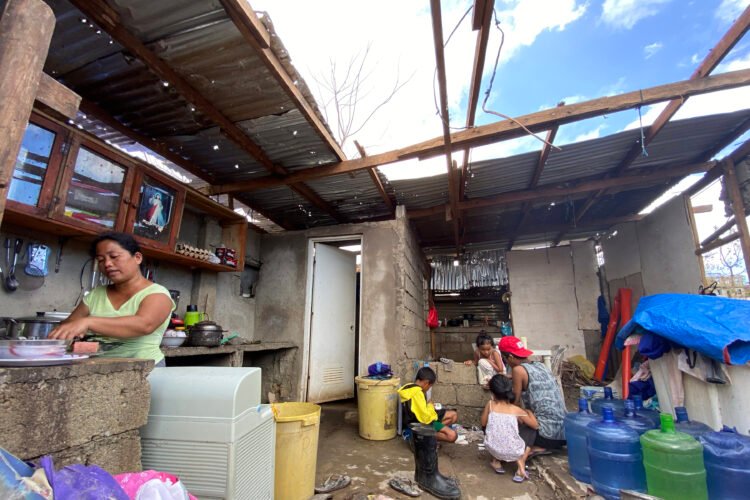 A woman prepares a meal for her children amid the lack of roof cover in Barangay Lipata. [Erwin Mascariñas/Greenpeace]