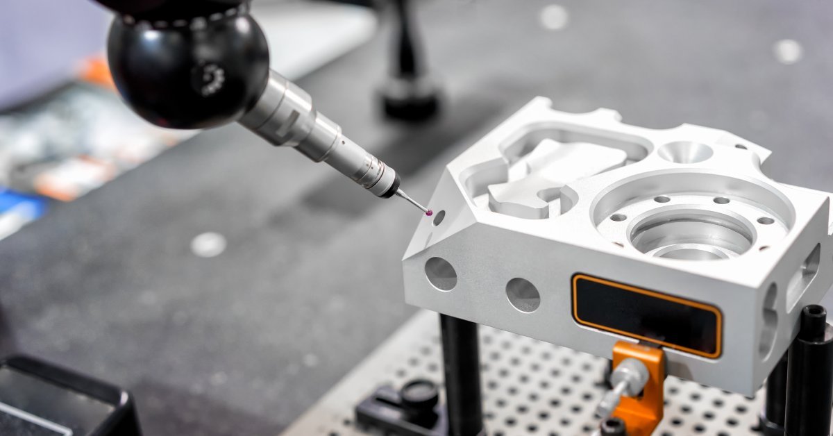 A Coordinated Measuring Machine (CMM) with a small stylus aligning with an indentation on a metal part.