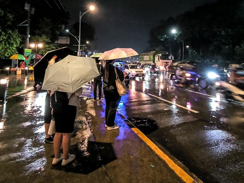 Commuters wait for rides along well-lighted Elliptical Road in Quezon City on Monday night (Nov. 3, 2025). It has been raining in Metro Manila the whole day but it is not directly affected by Typhoon Tino, which is battering parts of Visayas and Mindanao. (PNA photo by Joan Bondoc)