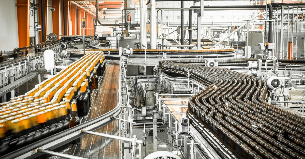 A beer bottling factory with multiple conveyor belts transporting hundreds of bottles of liquid throughout the facility.