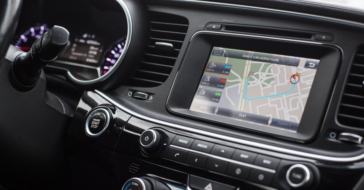 A sleek, black modern car dashboard with silver trim. An active GPS is in the center of the dashboard.