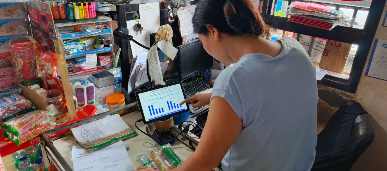Sari-sari store owner reviewing inventory data on a digital device