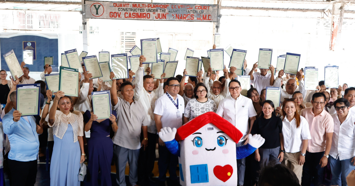 Officials and homeowners gather for the turnover of land titles under the government's housing initiative.