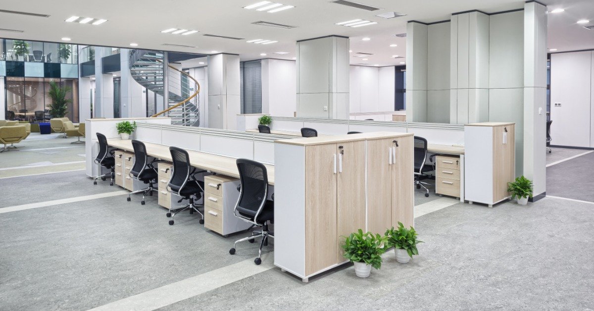 An office with several workstations that each have a file drawer organizer. A spiral staircase is in the background.