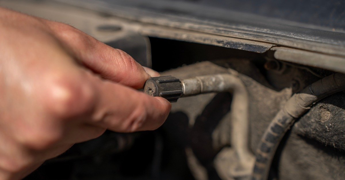 A person is grabbing a valve with their forefinger and thumb. The valve is attached to bigger mechanical parts.