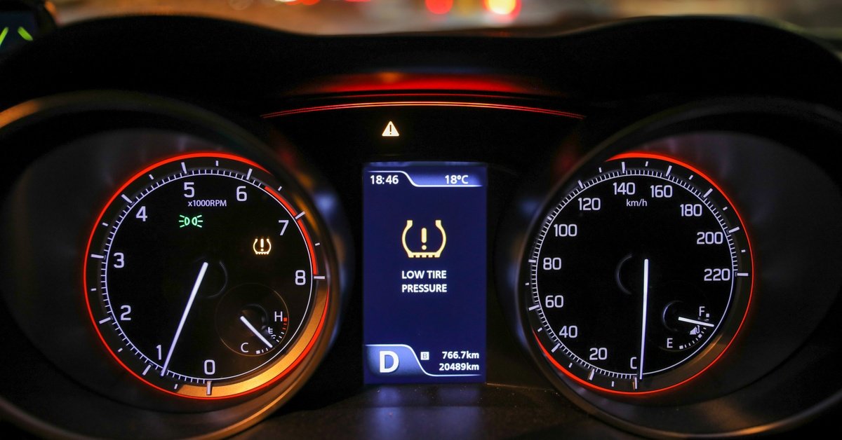 A close-up of the instrument cluster of a modern vehicle with the center interface displaying a "LOW TIRE PRESSURE" warning.