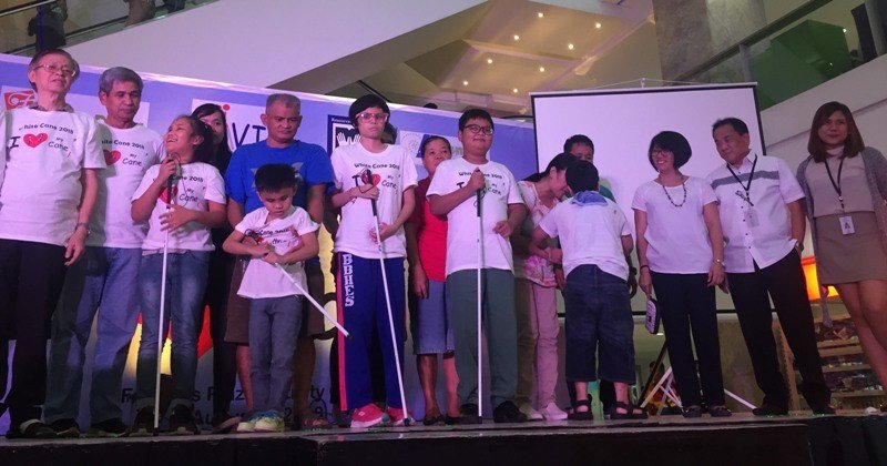 Farmers Plaza officials, headed by Property Manager Ceasar Valencia (second from right), distribute white canes to visually-impaired children who attended the White Cane Safety Day celebration in Araneta Center. 