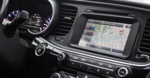 A sleek, black modern car dashboard with silver trim. An active GPS is in the center of the dashboard.